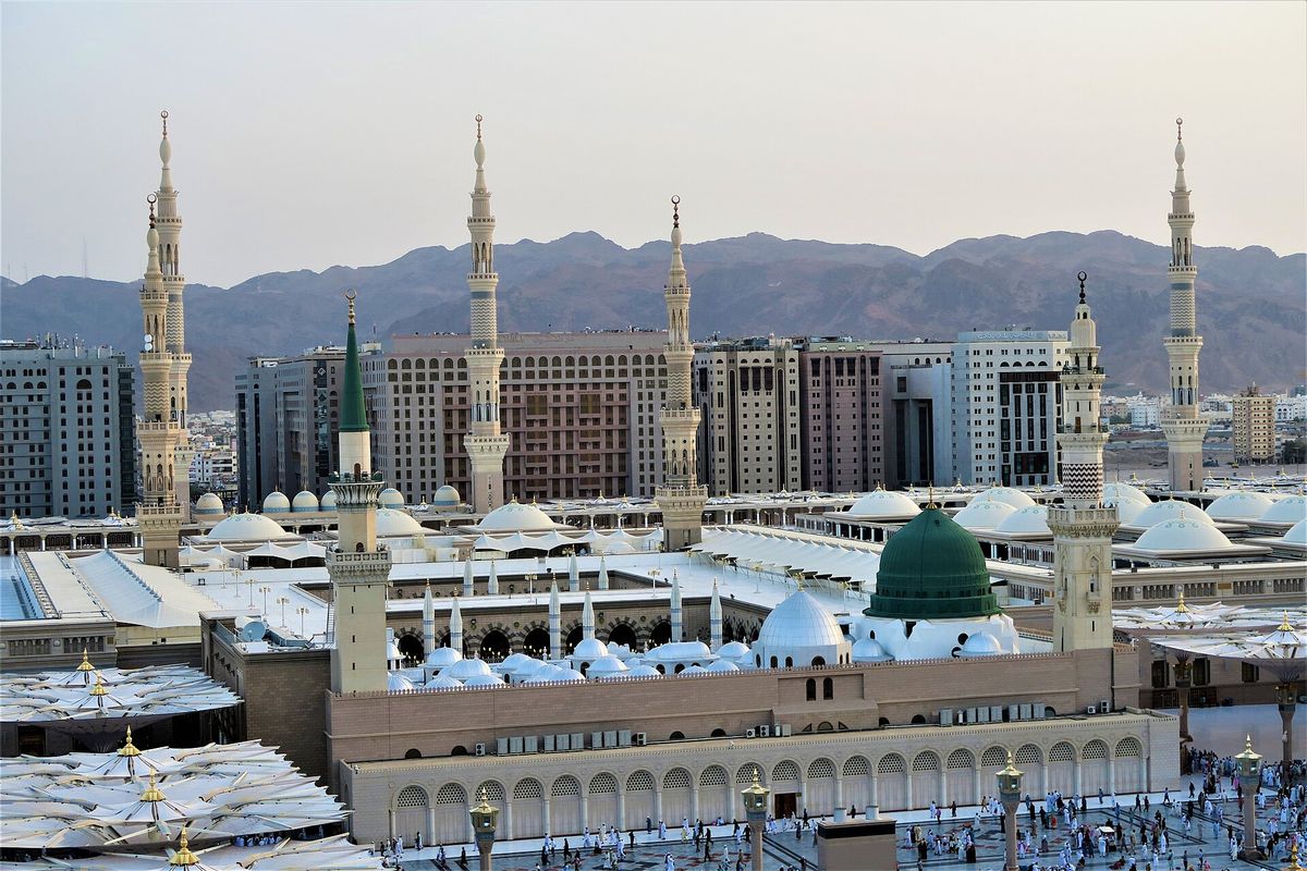 Al-Masjid an-Nabawi in Madinah seen from above, with its green dome and minarets.